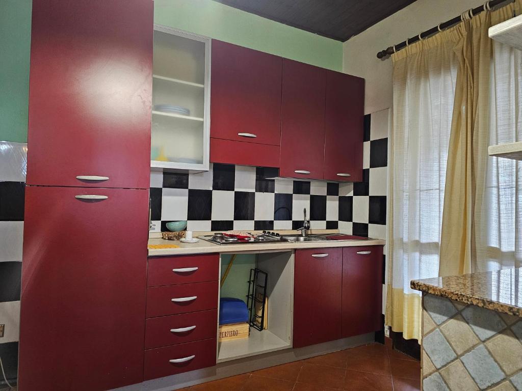 a kitchen with red cabinets and a sink at Il Rifugio Sul Mare in Budoni