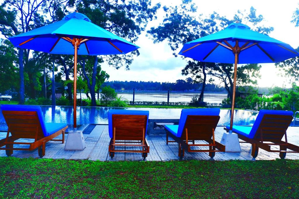 a group of chairs and umbrellas next to a pool at Diya Dahara Lake Resort in Tissamaharama