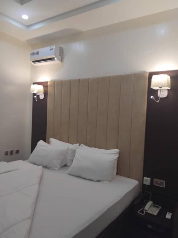 Un dormitorio con una cama con sábanas y almohadas blancas. en Villa Engracia Suite, en Kaduna