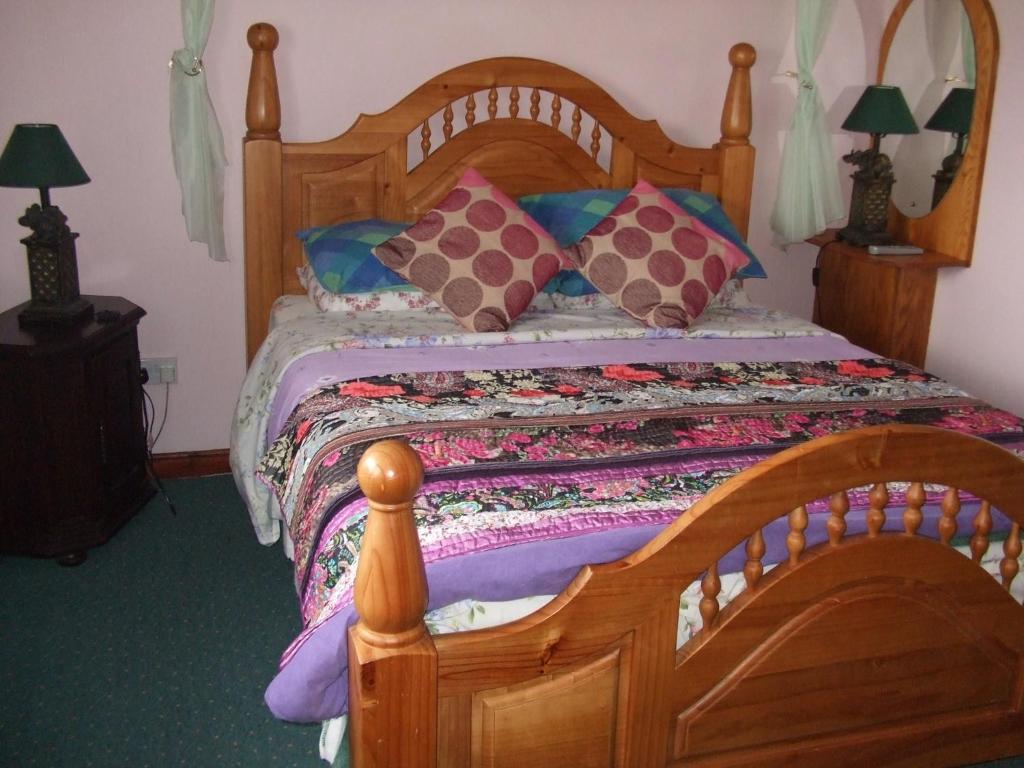 a bedroom with a wooden bed with colorful pillows at Friary View Bed & Breakfast in Killarney