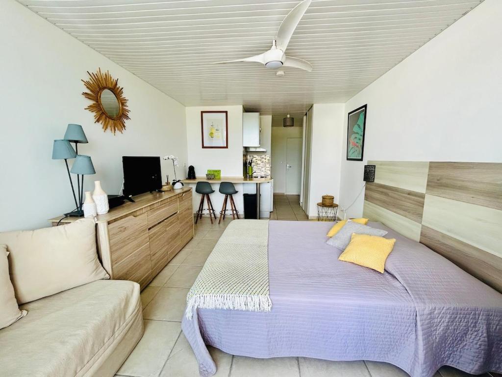 a bedroom with a large bed and a couch at Soleilcaraïbe Studio - direct beach access Gosier in Le Gosier