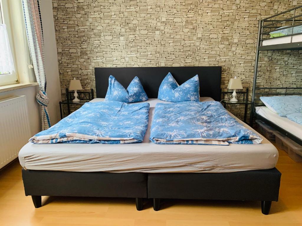 Schlafzimmer mit einem Bett mit blauer Bettwäsche und Kissen in der Unterkunft Moderne Ferienwohnung - Top Lage nahe Skigebiet & Wanderwegen in Sankt Andreasberg