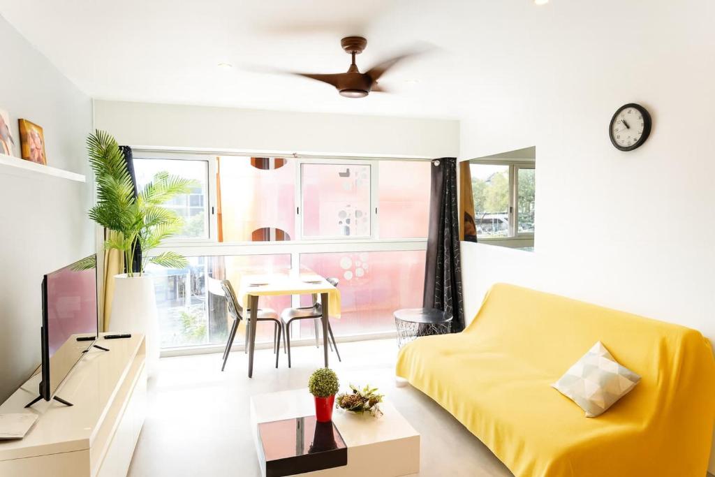 a living room with a yellow couch and a table at BBL Ferry Lodge in Papeete