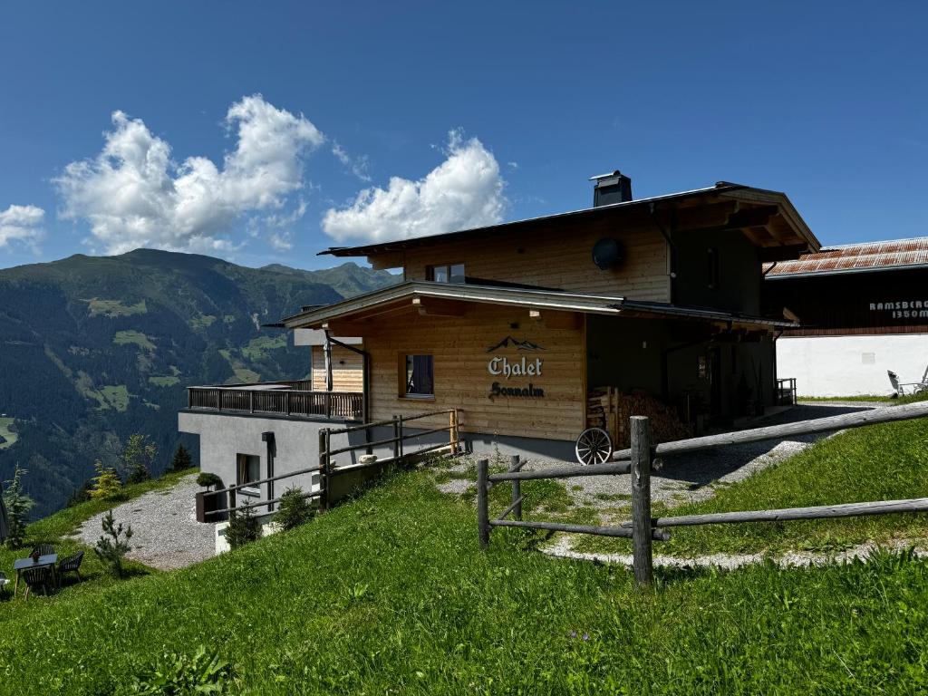 a building on the side of a hill with a fence at SonnenChalet Schlittenstadl in Ramsau im Zillertal