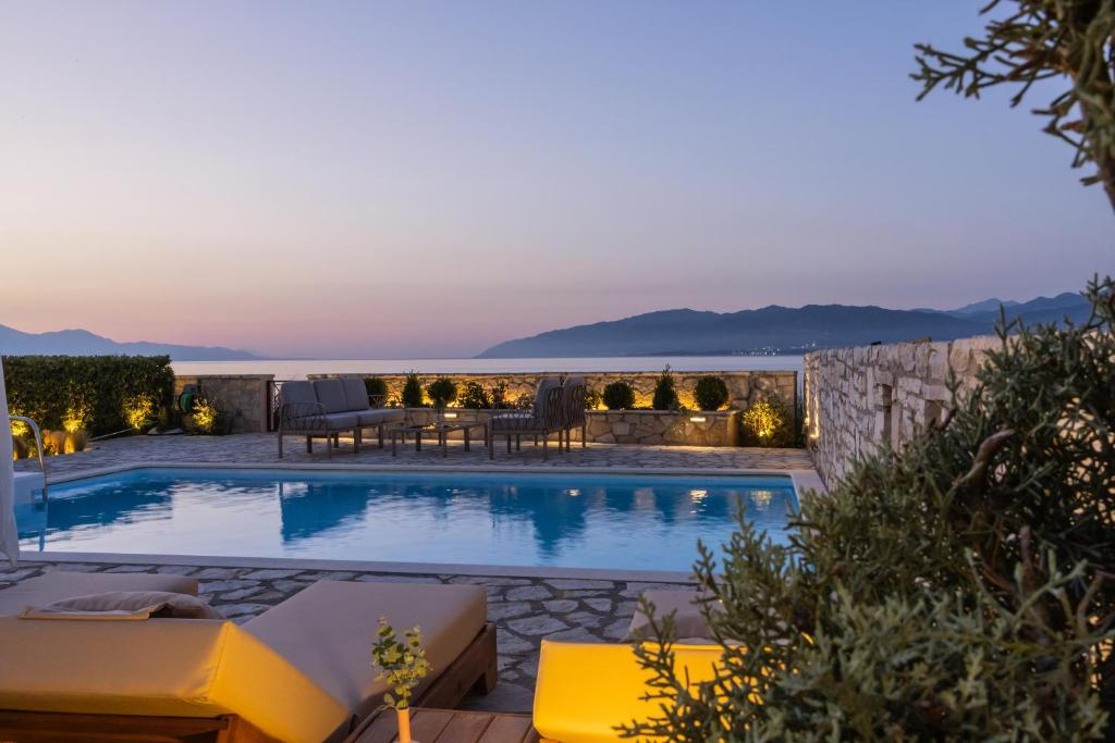 a swimming pool with a view of the ocean at night at Seafront Villa Ciel with Private Pool in Nafpaktos in Nafpaktos