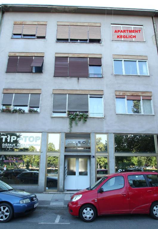 czerwony samochód zaparkowany przed budynkiem w obiekcie Apartment Keglich w Zagrzebiu