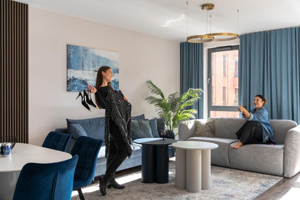 a woman standing in a living room with a man at Scala City Center Premium Apartments with Parking by Lion Apartments in Gdańsk