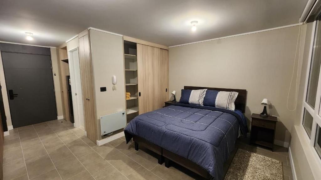 a bedroom with a bed with a blue blanket at Departamento Estudio, ubicación inmejorable, con estacionamiento in Los Ángeles