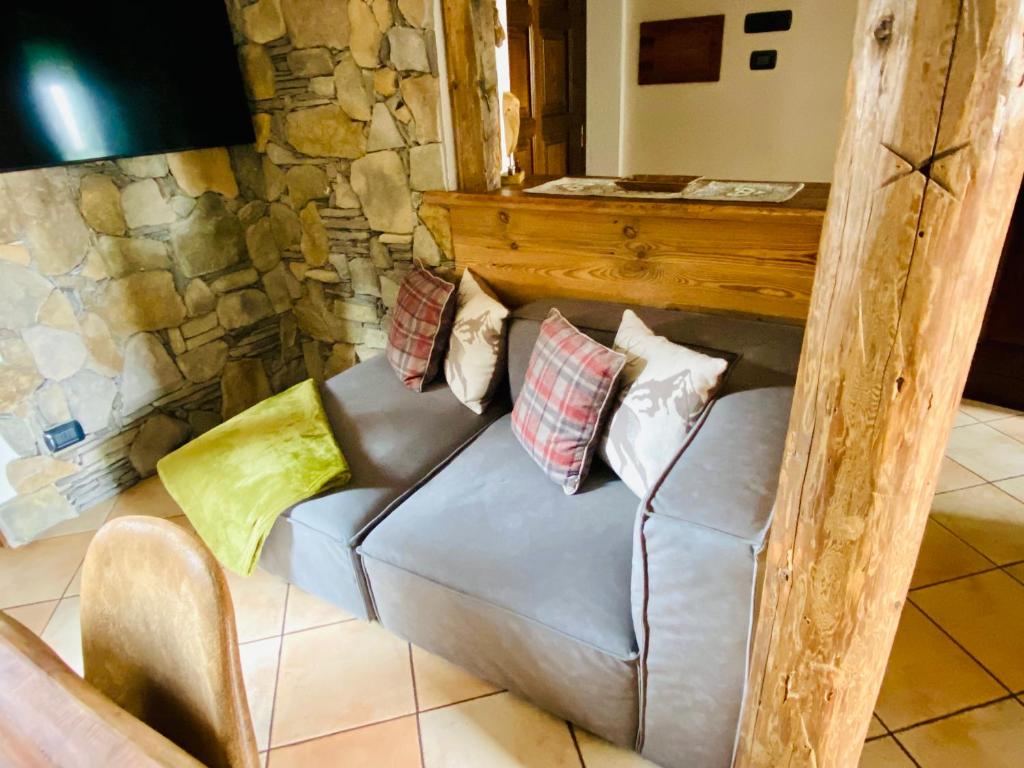 a couch in a room with a stone wall at Le petit bijou in Aosta