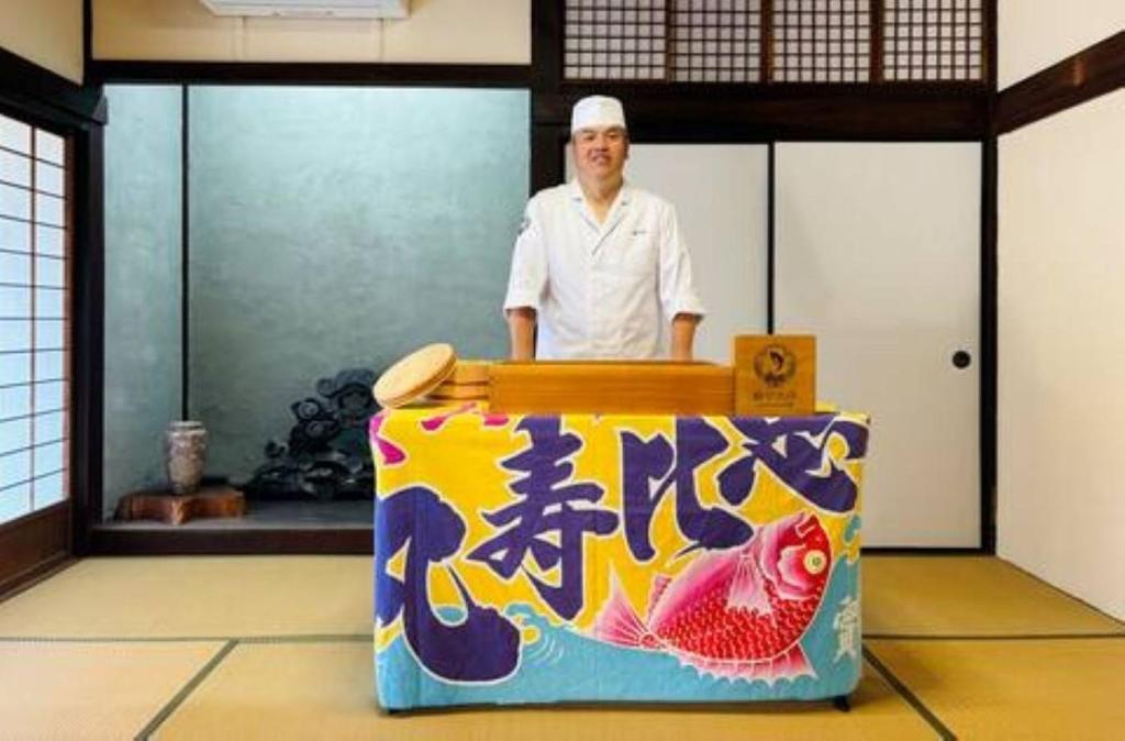 un homme debout derrière une table avec une boîte dans l'établissement Toyotakeyashiki - Vacation STAY 37187v, à Towa