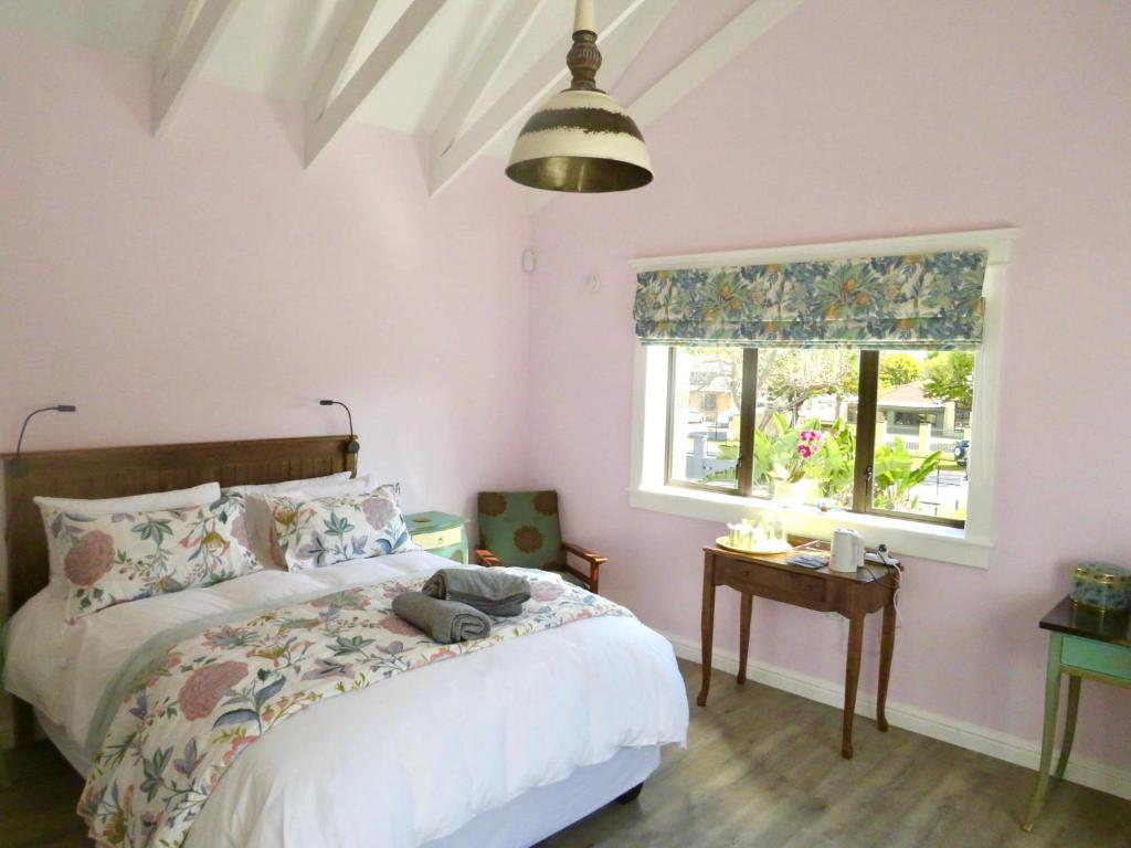 - une chambre avec des murs roses et un lit avec une fenêtre dans l'établissement Whistlewood Guesthouse Walmer, Port Eizabeth, à Port Elizabeth