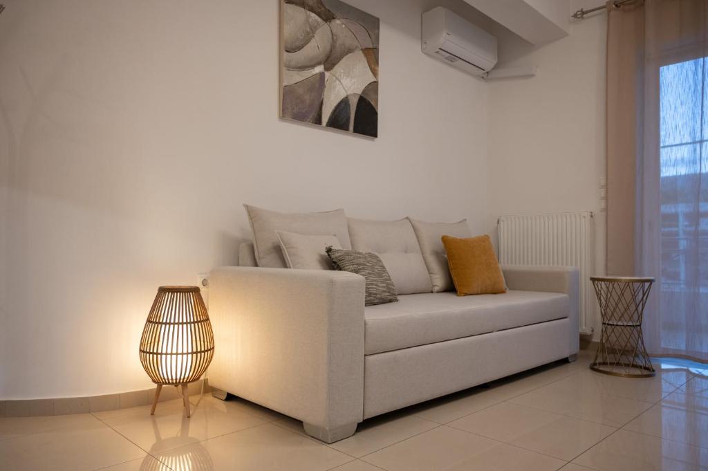 a living room with a white couch and a lamp at Pnoé Luminous Apartment in Nafplio