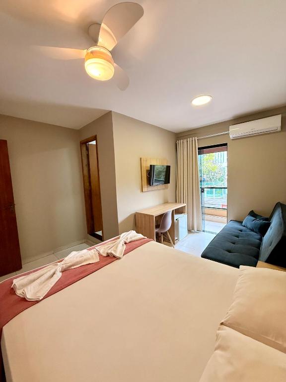 a bedroom with a bed and a couch at Summer Suítes - Passagem in Cabo Frio