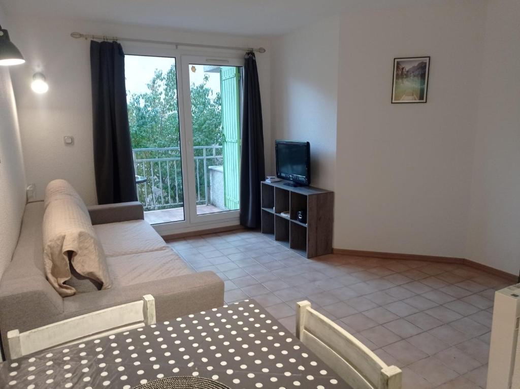 een woonkamer met een bank en een tv bij T2 proche thermes, nature in Digne-les-Bains