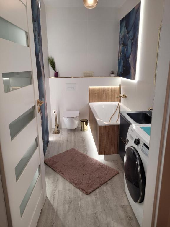 a small bathroom with a sink and a washing machine at Apartament Cień Wiatru z Widokiem na Jezioro i Netflixem in Charzykowy
