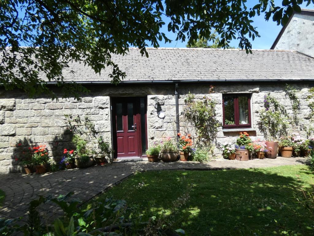 a stone cottage with a red door and some plants at Brunnion Cottage in Hayle