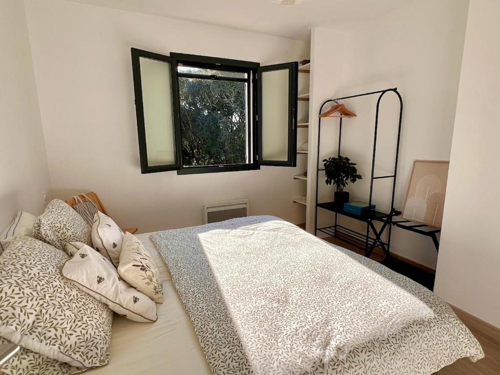 Un dormitorio con una cama blanca con una ventana. en Villa Mimosa, en Venasque