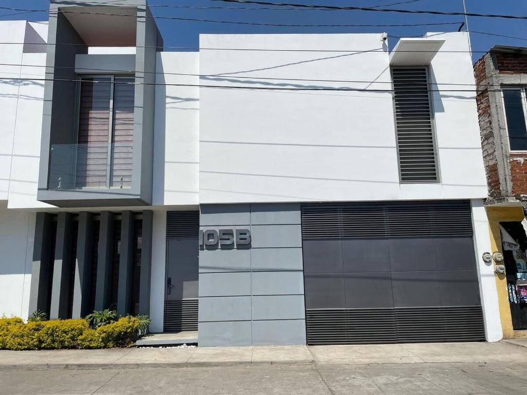 a white building with two garage doors on a street at Hogar Tu Santuario Uruapan in Uruapan del Progreso