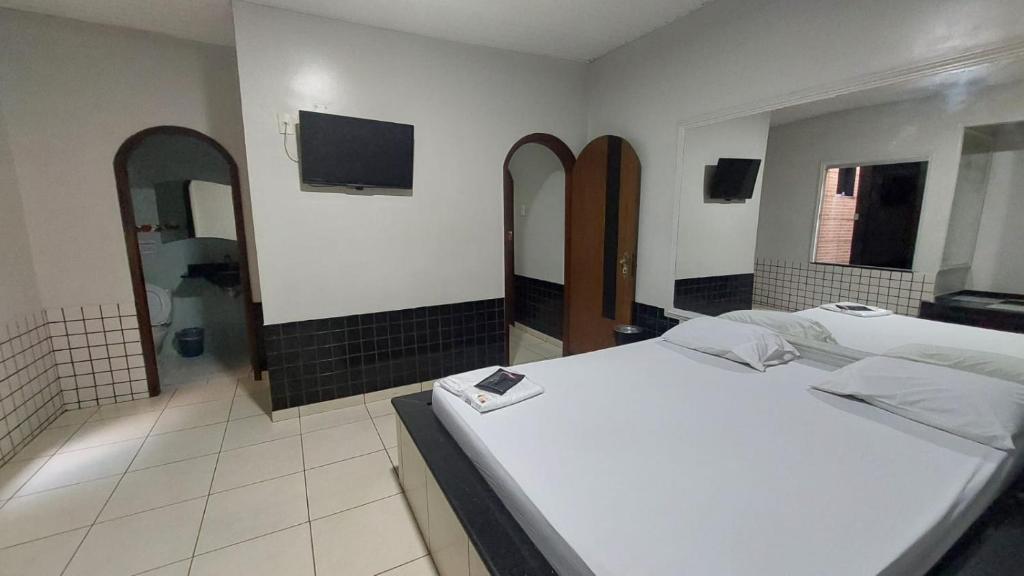 a bedroom with two beds and a bathroom with a tv at Motel Só Prazer na COP 30 aptos in Marituba