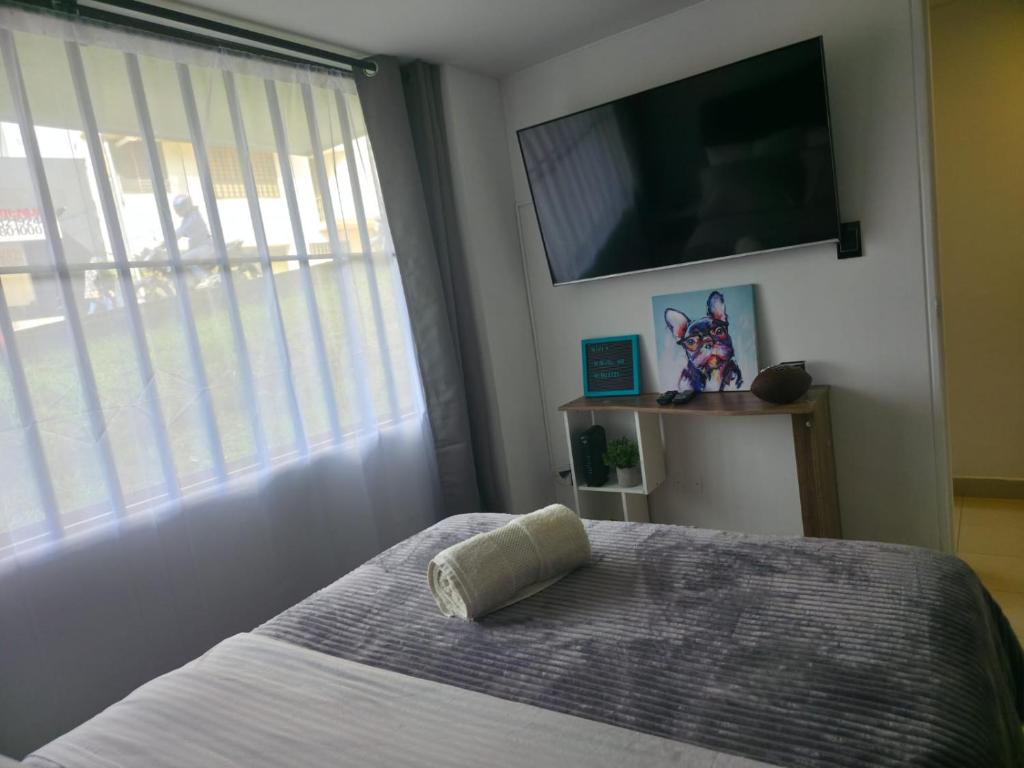 a bedroom with a bed with a television on the wall at Excellent Studio Apartment in Zona Rosa Milan in Manizales