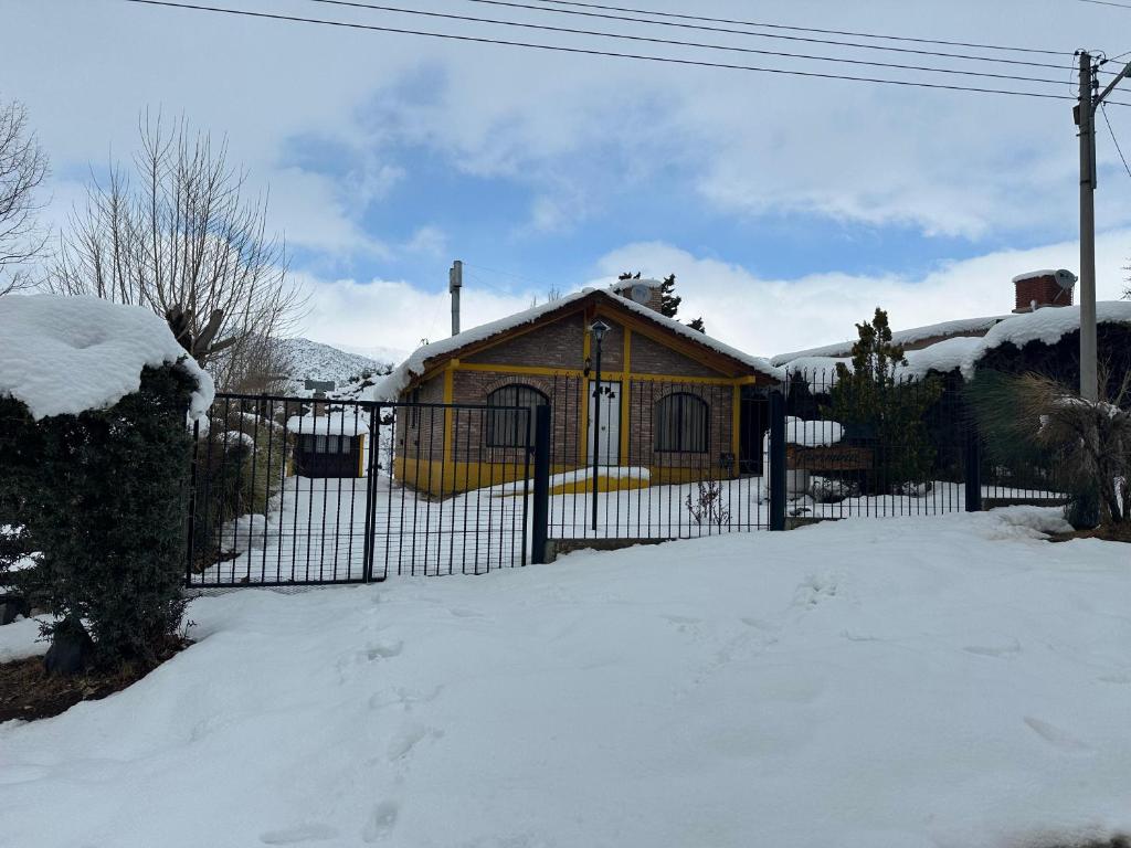 una cerca frente a una casa en la nieve en Cabaña Taormina, en Potrerillos