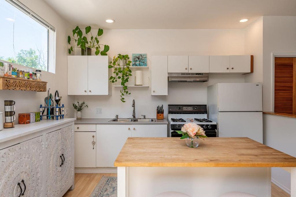 a kitchen with white cabinets and a wooden table at The Malibu Retreat Apartments in Malibu Beach
