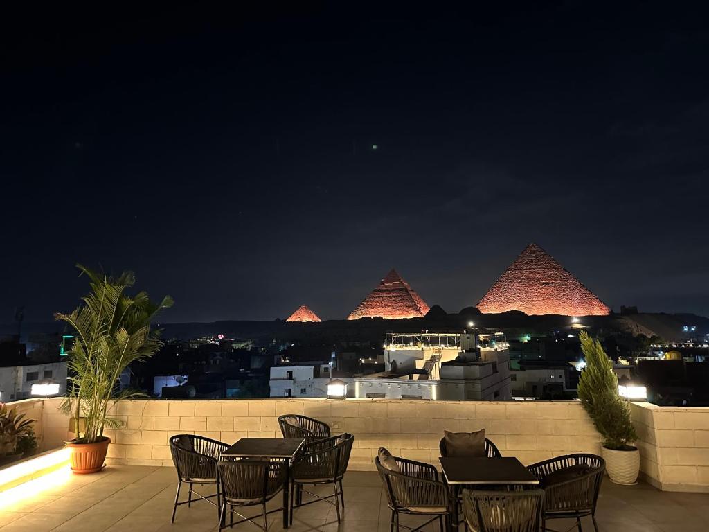 a group of tables and chairs on a balcony at night at The kings of pyramids view inn in Cairo