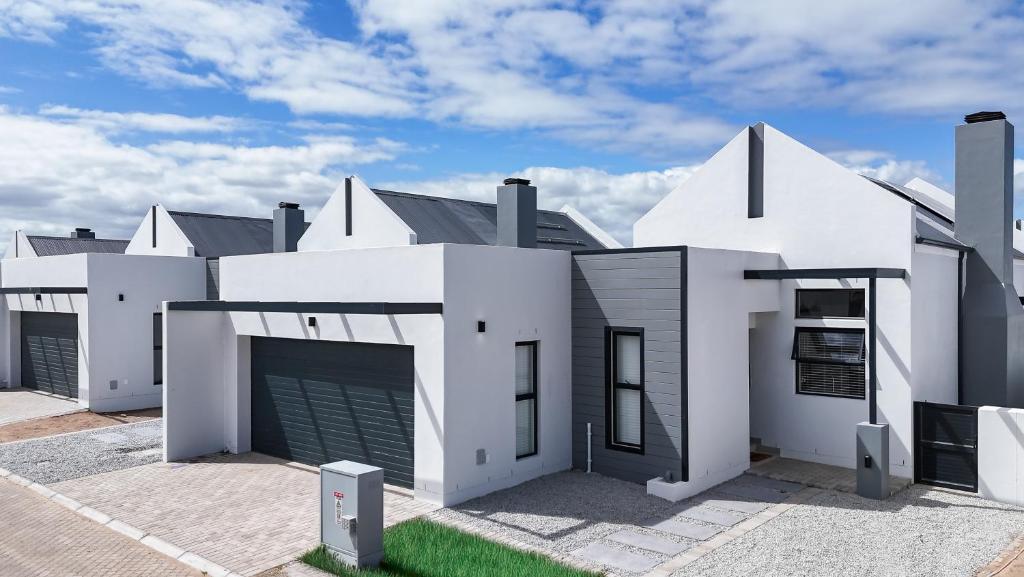a white house with a garage in a parking lot at Modern 2 Bed Home with Solar & Braai Langebaan in Langebaan