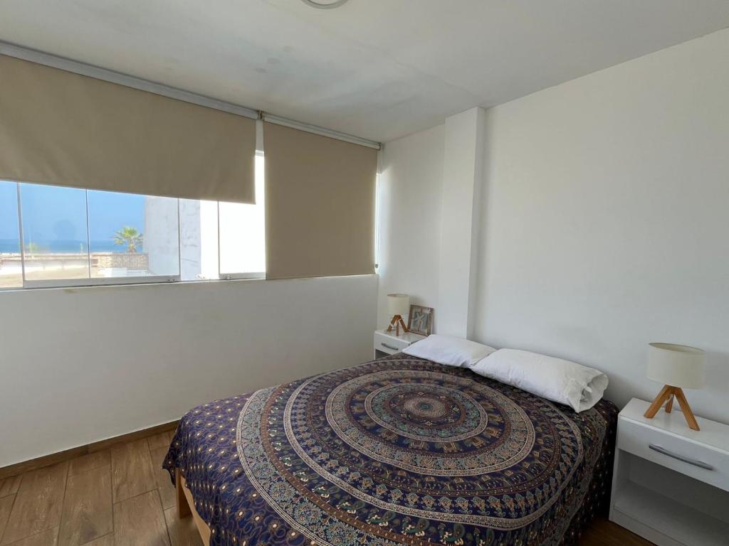a bedroom with a bed and a large window at Departamento con salida a la playa in Punta Negra
