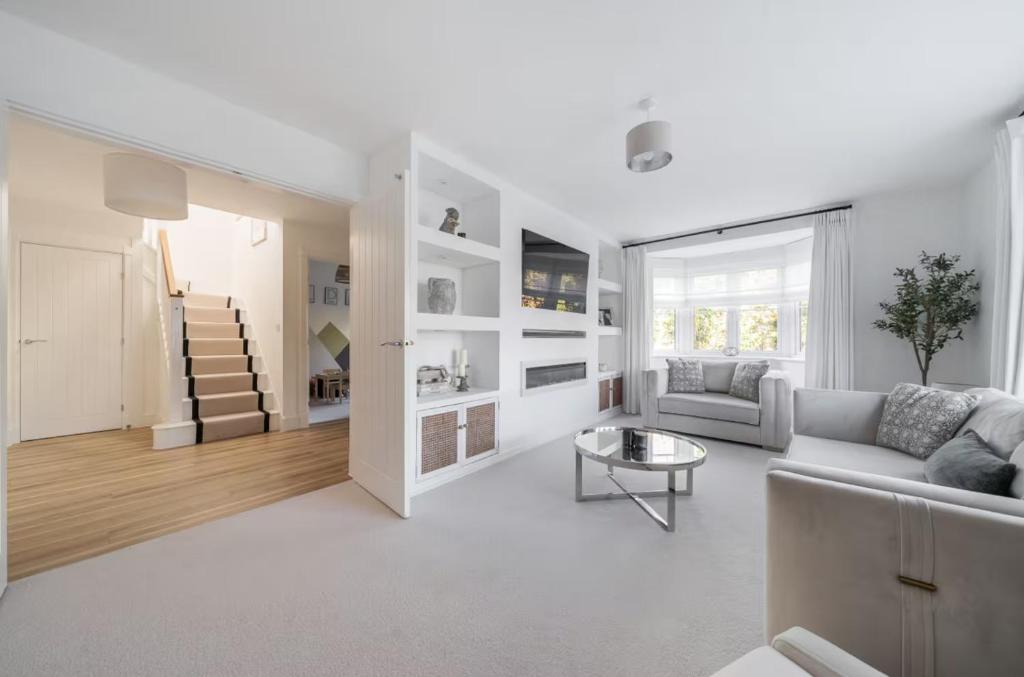 a white living room with a couch and a table at Spacious 4 Bed Home for Contractors & Families in Blunham