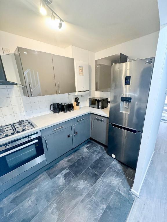 a kitchen with a stainless steel refrigerator and cabinets at Modern 2-Bed w Parking & Garden in Woolwich