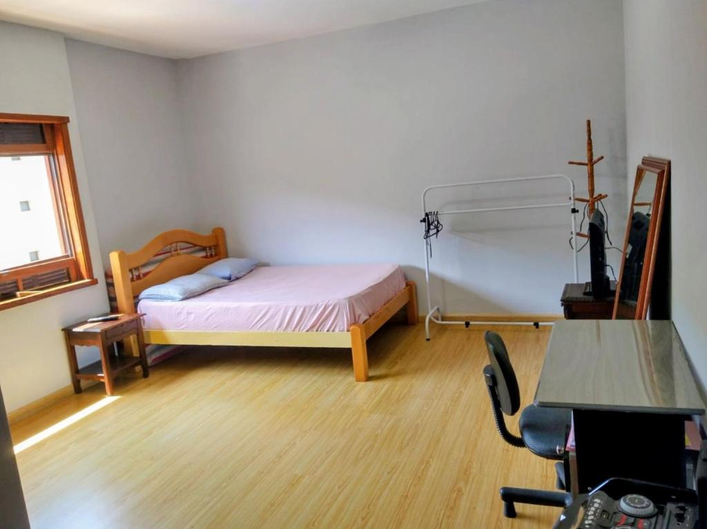 una camera da letto con un letto, una scrivania e una sedia di Apartamento amplo 2 quartos no centro ad Águas de Lindóia