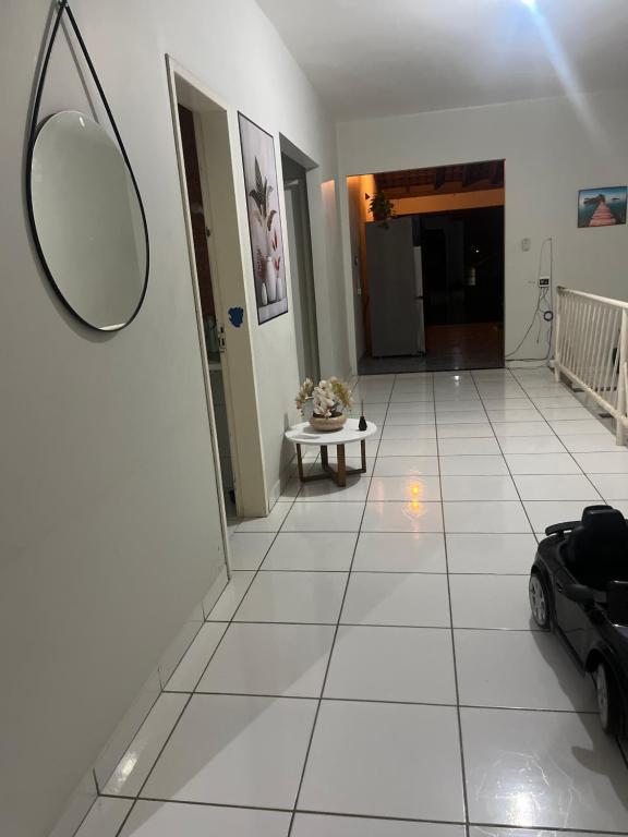 Un pasillo con un espejo y un coche sobre un suelo de baldosas. en Hostel Franca, en Montes Claros