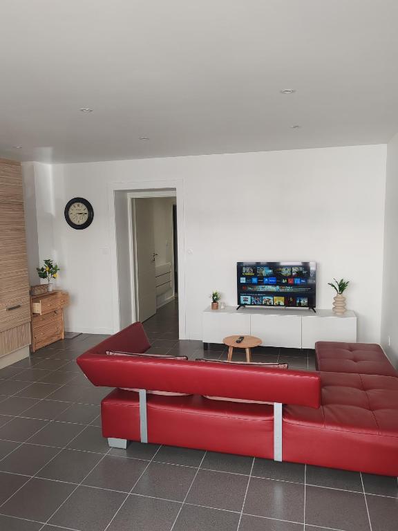 a red couch in a living room with a tv at Tini in Hayange