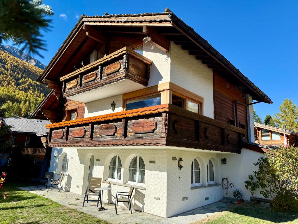 a house with a wooden roof and some chairs at Chalet Bärgheimet Saas-Fee in Saas-Fee
