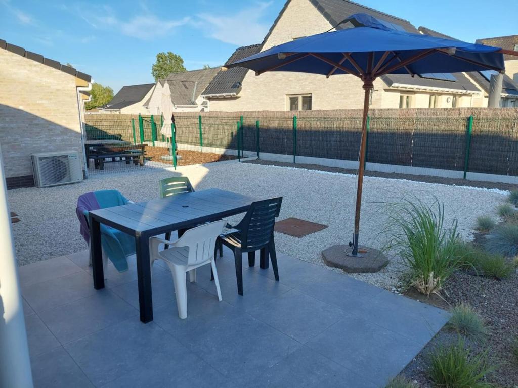 Un patio con una mesa y sillas y una sombrilla. en Westhinder II H9, en Witte Burg