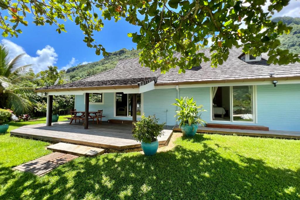 a house with a wooden deck in the yard at Villa Ohana - 4BR Beachfront Villa in Paopao