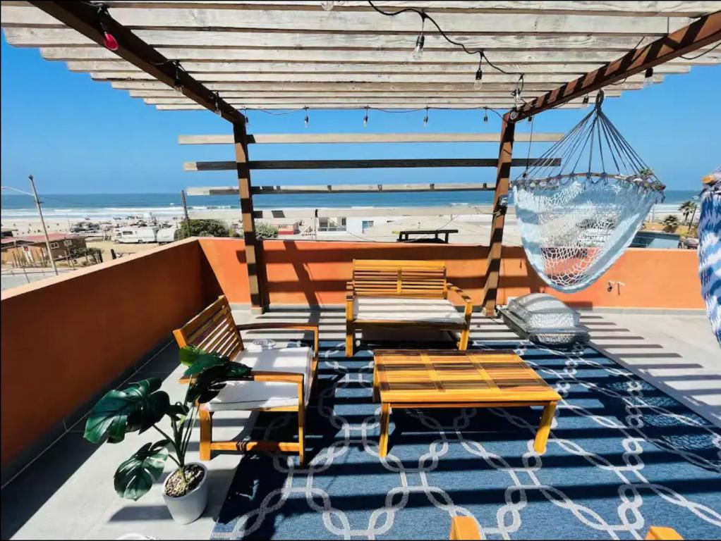 a patio with chairs and hammocks on a roof at Steps to the sand with Balcony and Ocean View in Rosarito Beach