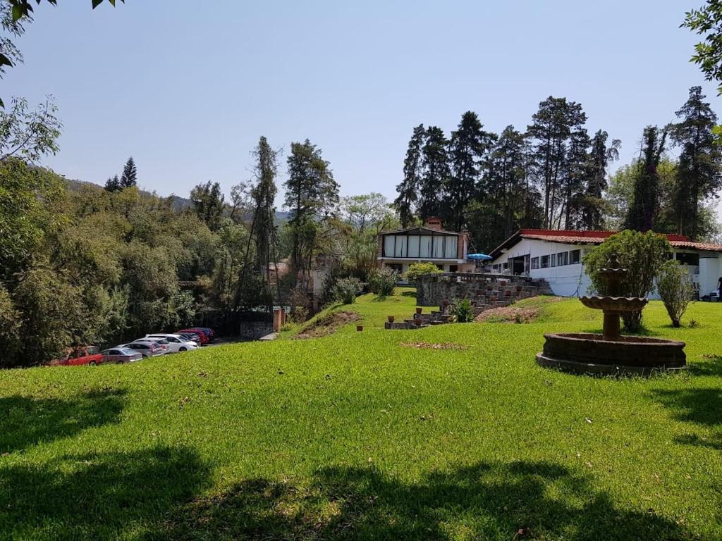 eine grüne Wiese mit in einem Hof geparkten Autos in der Unterkunft Casa Grande, Casita, Gran Jardín, Juegos para 19 personas en el Pueblo in Valle de Bravo