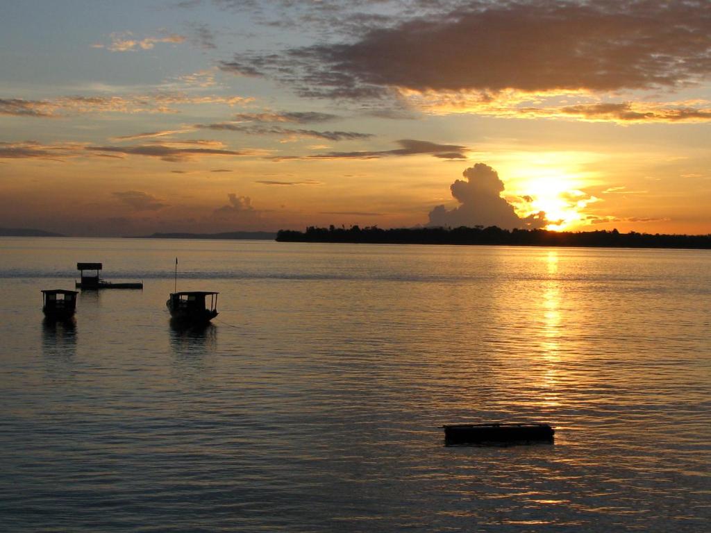 a sunset on a lake with boats in the water at Bunaken Cha Cha Nature Resort in Bunaken