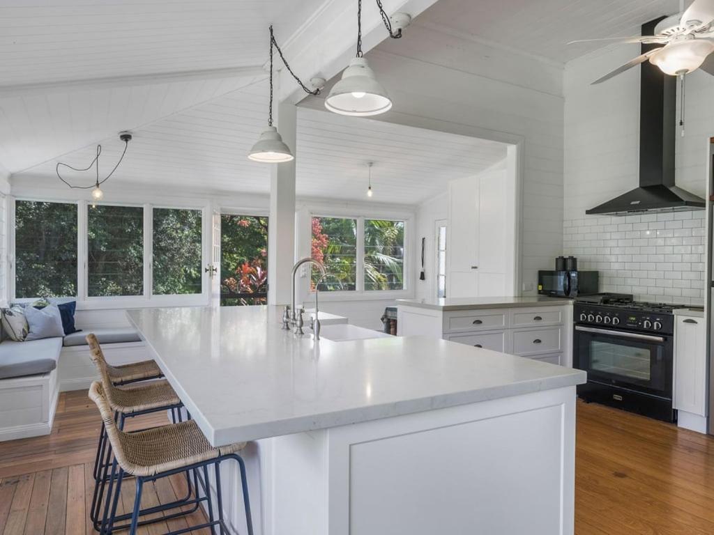 a white kitchen with a large white counter top at Fig Tree House in Teven