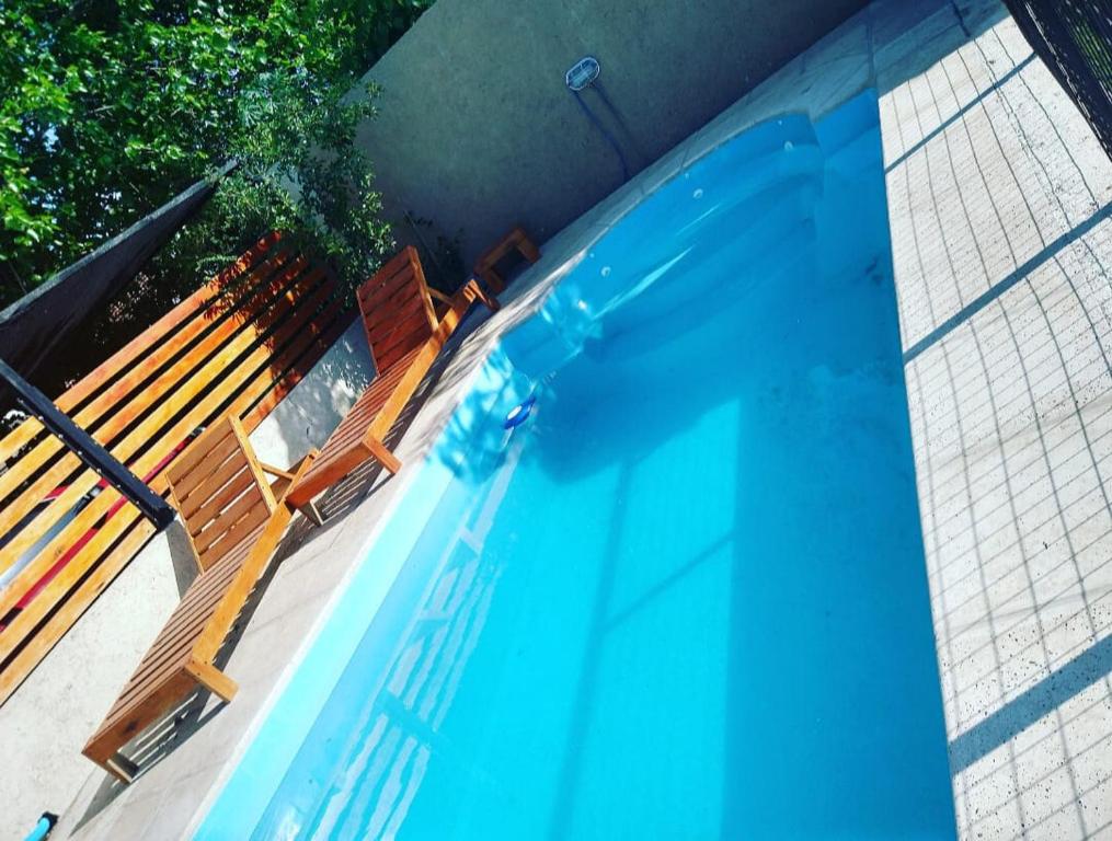 a swimming pool with two chairs and a bench at Departamento familiar con pileta exclusiva in Villa Carlos Paz