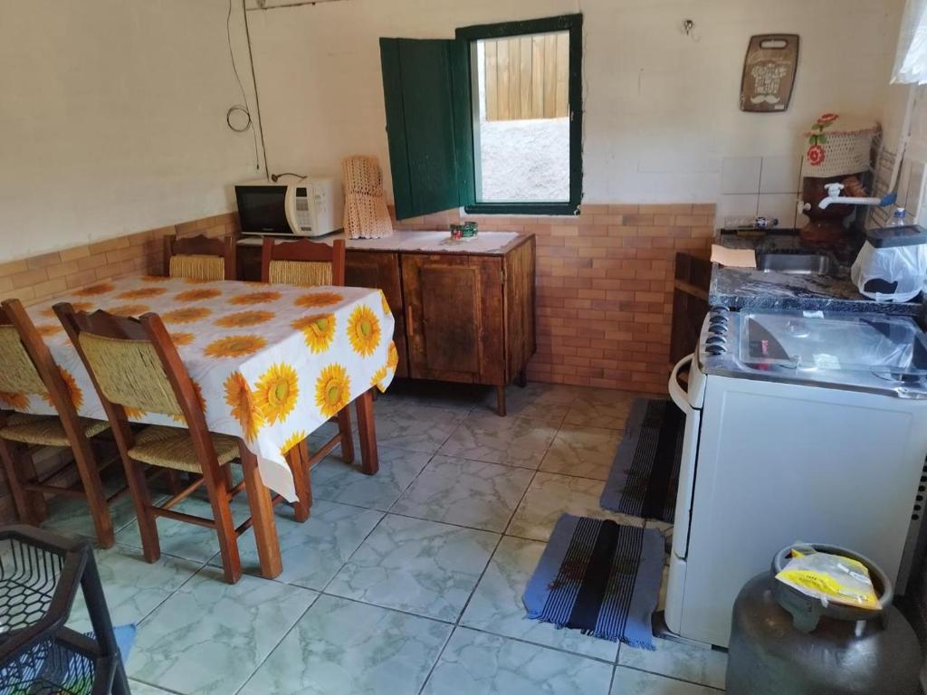 a kitchen with a table and a table and a stove at Chácara Pedacinho do Céu in Extrema