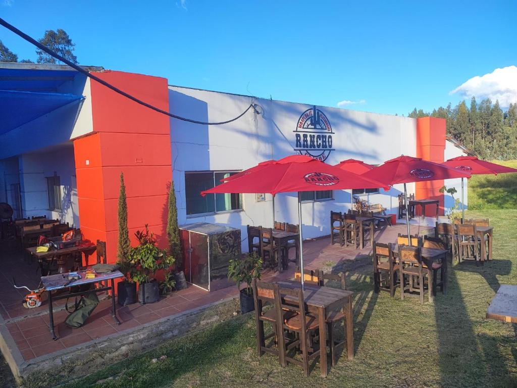 a building with tables and umbrellas outside of it at Hospedaje & Restaurante Rancho Grande Tocancipá SAS in Tocancipá