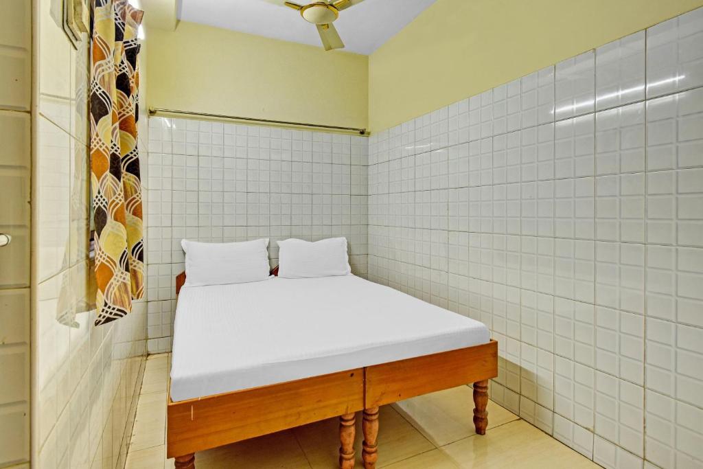 a small room with a white bed in a wall at Hotel O Dream Palace Guest House Near Marina Beach in Chennai