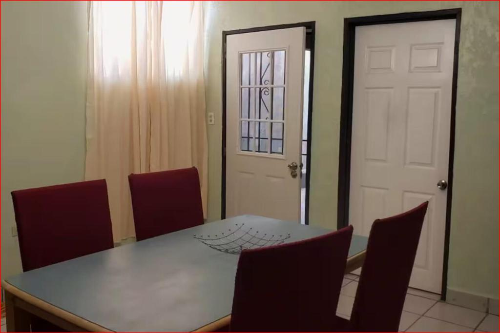 comedor con mesa, sillas y puerta blanca en AlegreA -2 br apartment with secure parking included, en Playas de Rosarito