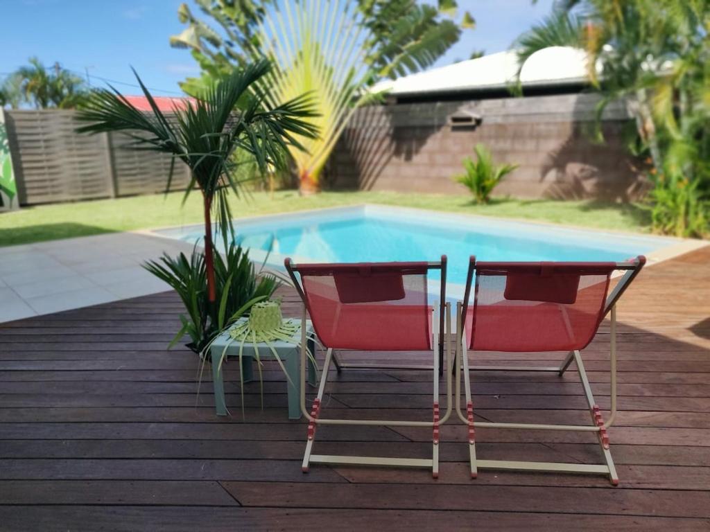 Dos sillas y una mesa junto a una piscina. en Vaiava Lodge, en Punaauia