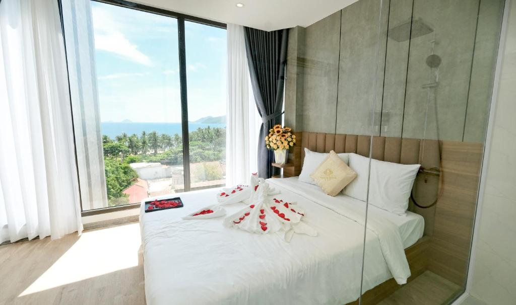 a bedroom with a white bed and a large window at Prague Nha Trang Hotel in Nha Trang