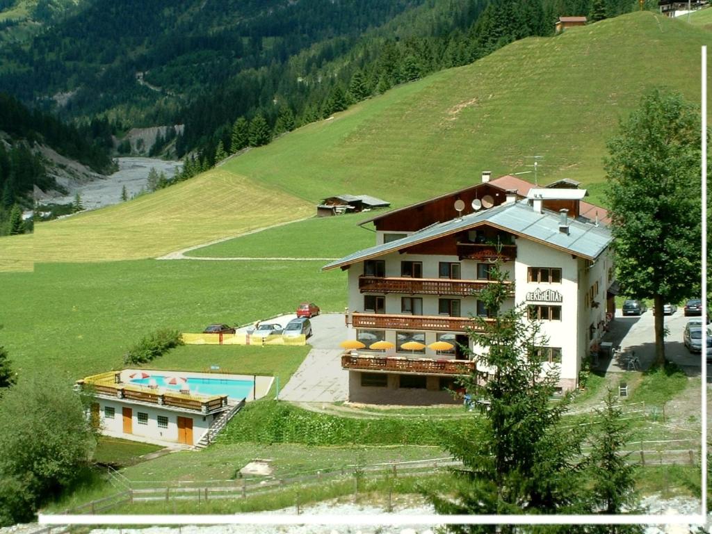 a building on a hill next to a green field at Gasthof Bergheimat in Boden