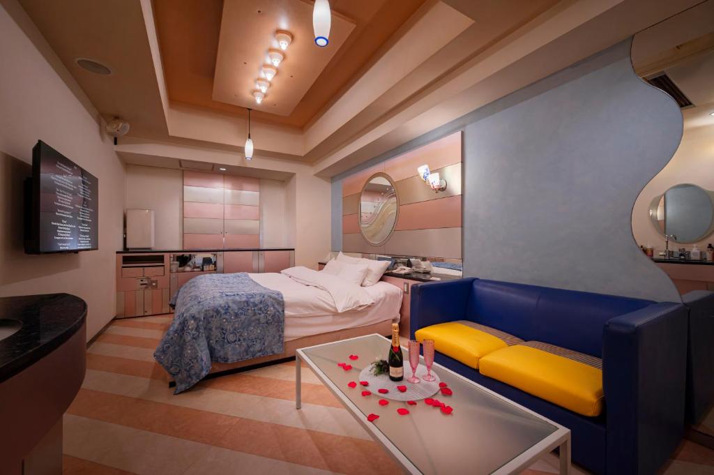 a bedroom with a bed and a couch and a table at Hotel Grand Garden (Adult Only) in Yokohama